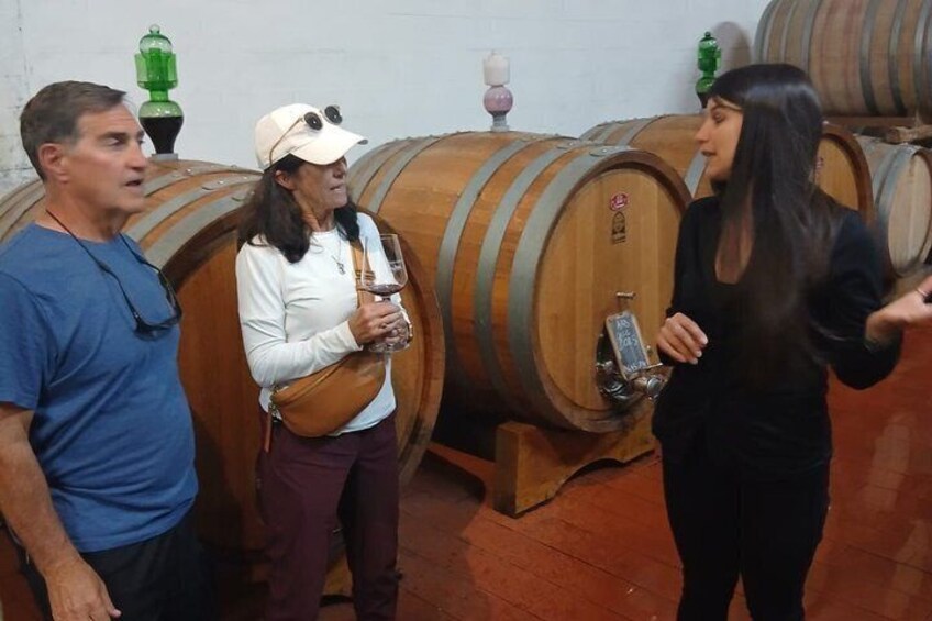 Tres personas en una bodega con barricas de madera. 2