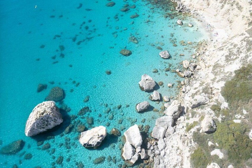 A turquoise sea with rocky outcrops and clear water. 5