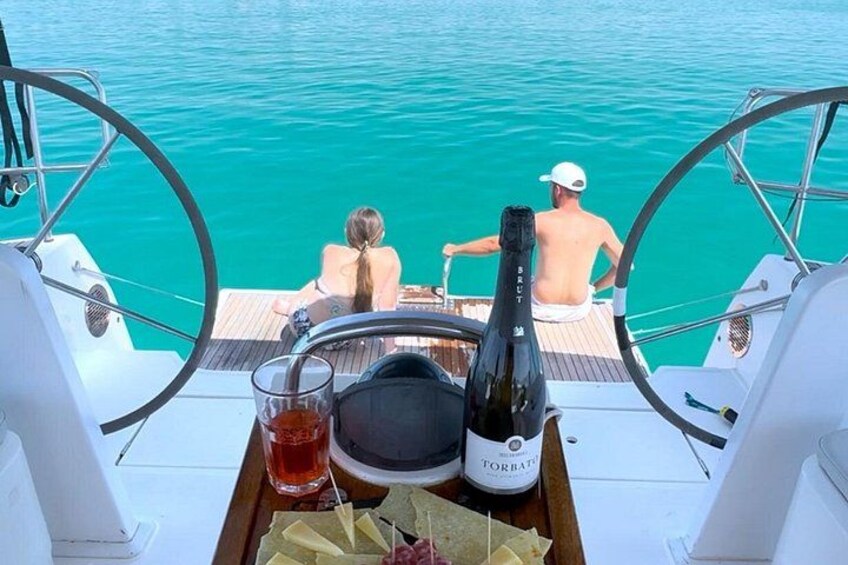 A boat with two people on deck, a bottle of Torani, and a glass of red liquid. 3