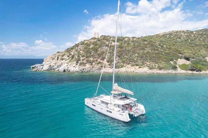 A sailboat on turquoise waters with a rocky island in the background. 4