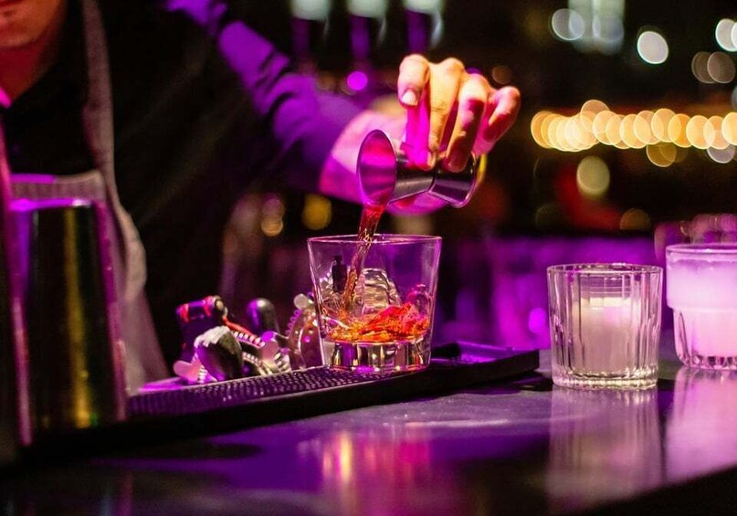 A bartender pouring a drink into a glass. 2