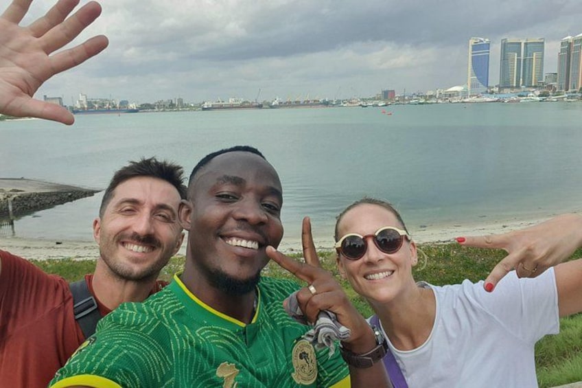 Three people posing by a waterfront with a city skyline in the background. 1