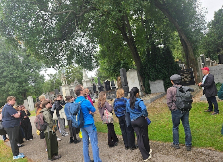 A group of people visiting a cemetery with various tombstones and memorials. 2