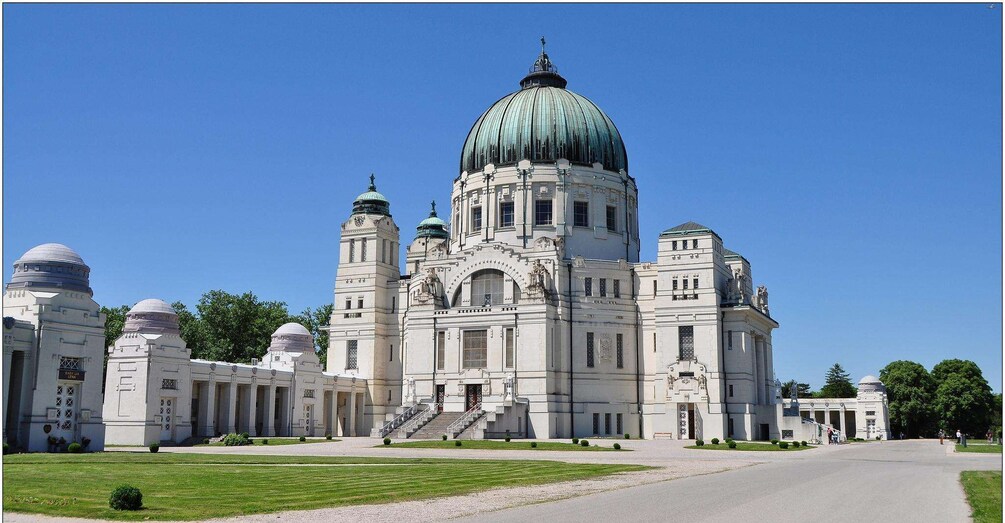 A large, ornate building with a prominent dome and multiple smaller domes, surrounded by a well-maintained lawn and a clear sky. 1