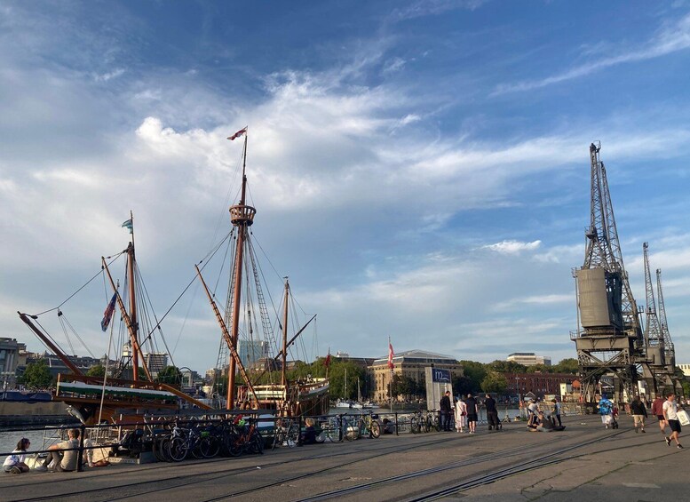 A harbor with a large ship, a crane, and a building with a blue sign. 1