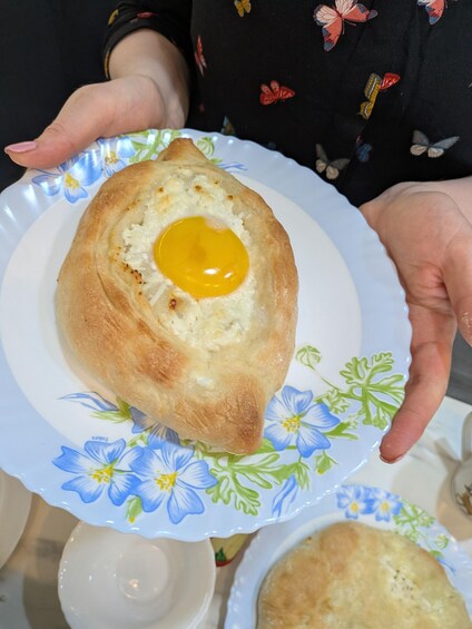 En person som håller i en tallrik med ett bakverk som innehåller ett stekt ägg. 4