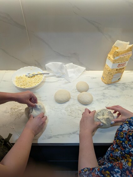 Un plan de travail de cuisine avec de la pâte, un saladier rempli de farine et un sac de farine. 1