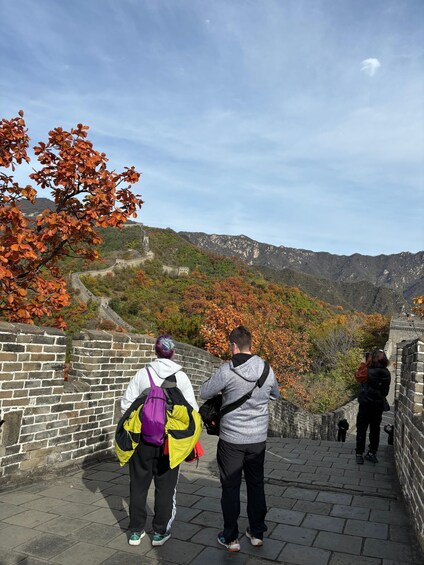 Two people standing on the Great Wall of China, overlooking the surrounding landscape. 2