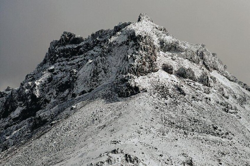 A snow-covered mountain peak with rugged terrain and rocky outcrops. 5