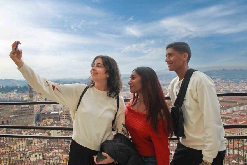 Three people taking a selfie with a cityscape in the background. 4