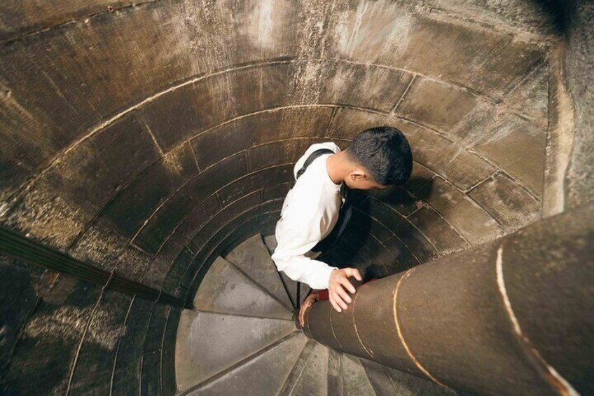 A person descending a spiral staircase in a stone building. 2