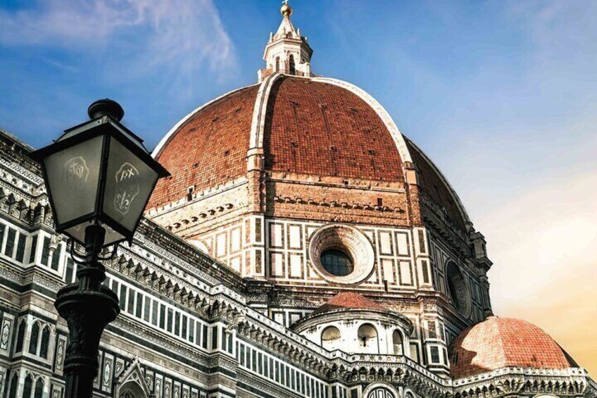 The Florence Cathedral's dome with intricate architectural details and a street lamp in the foreground. 1