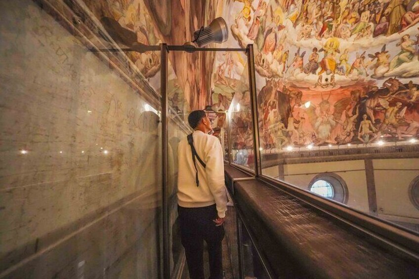 A person standing on a balcony, looking at a large mural on the wall. 5