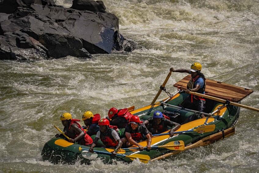 A group of people in a raft navigating a river with rapids. 2