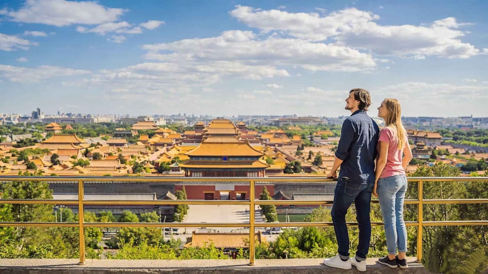 A couple overlooking a traditional Chinese architectural complex with tiered roofs. 1