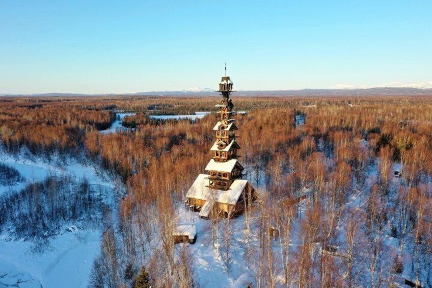 A wooden church with a bell tower surrounded by a snowy forest landscape. 4
