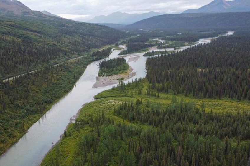 A river winding through a forested valley with mountains in the background. 2