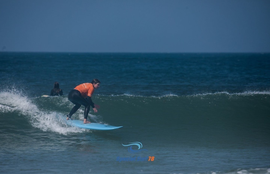 A surfer in an orange wetsuit riding a wave. 1
