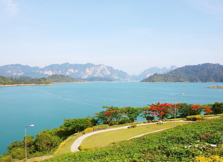 A coastal landscape with a clear blue sea, a pathway, and lush greenery. 2