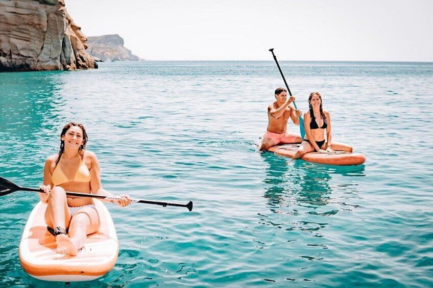 Three people on paddleboards in a calm sea with clear skies. 2