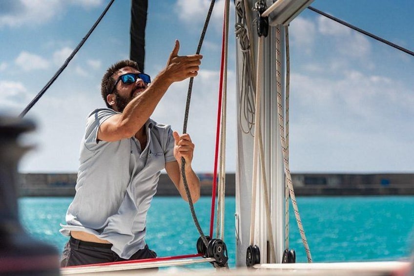 A person on a sailboat, holding onto a rope, with the ocean and a clear sky in the background. 3