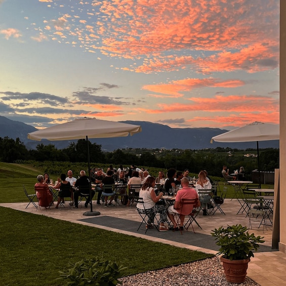 People dining outdoors at sunset with mountains in the background. 1