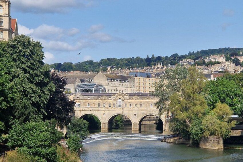 Eine Steinbrücke über einem Fluss, umgeben von Bäumen und Gebäuden. 3