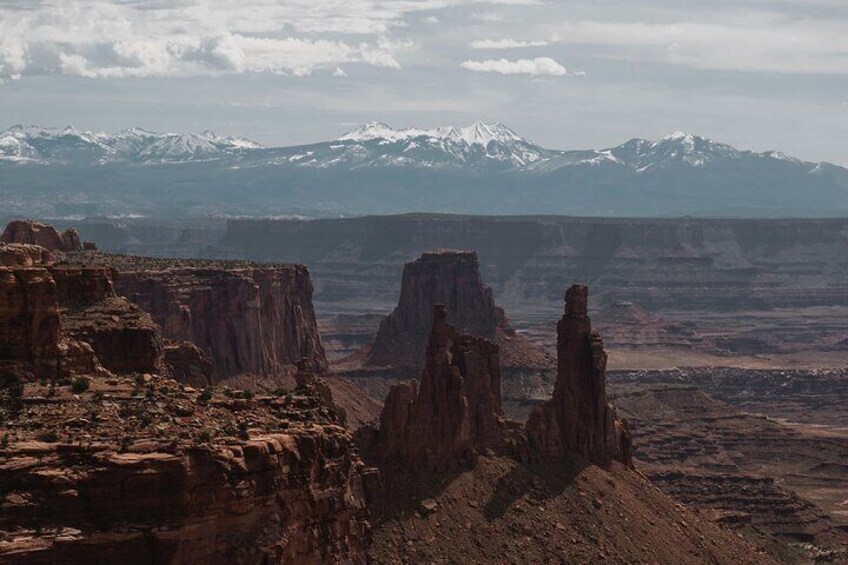 Un cañón con formaciones rocosas imponentes y montañas nevadas al fondo. 5