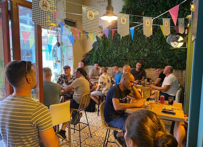 A group of people dining at an outdoor restaurant with a rustic interior and greenery decorations. 4
