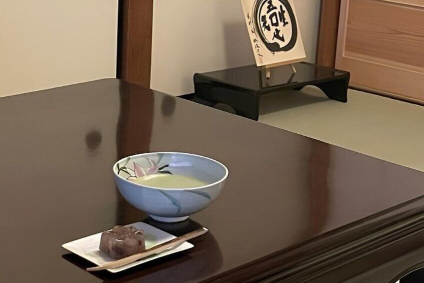 Une table en bois sur laquelle se trouvent un bol de soupe, des baguettes et une petite assiette de nourriture, le tout posé sur un set de table. 2