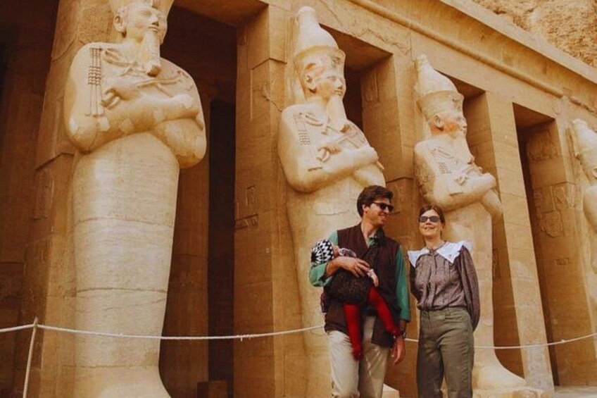 A large ancient Egyptian temple with statues of pharaohs and a rope barrier. 5