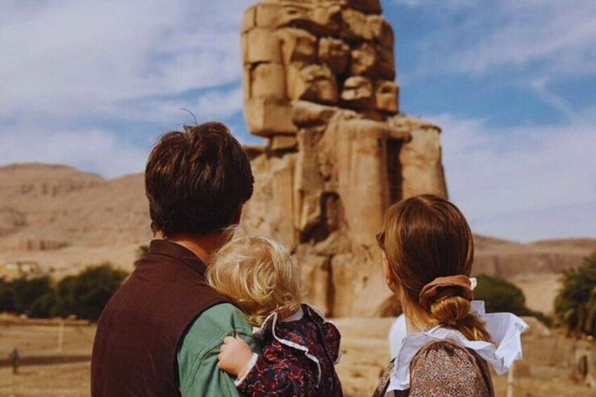 A family of three standing in front of a large stone structure. 1