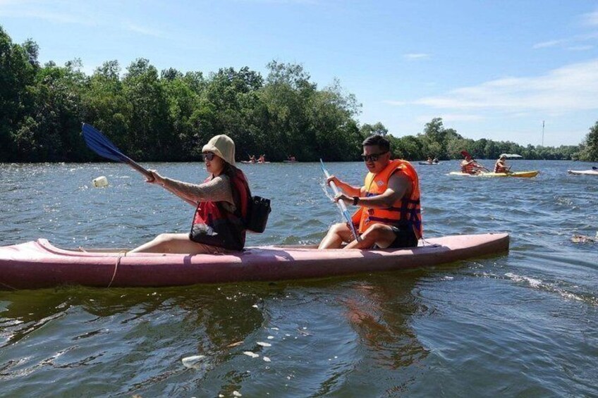 Two people kayaking on a river surrounded by trees. 1