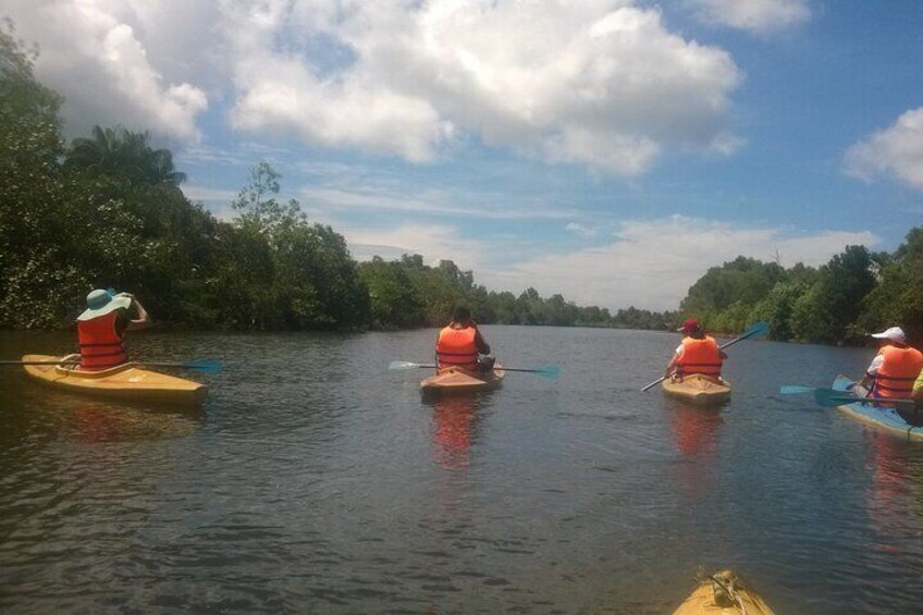 Three people kayaking on a calm river surrounded by lush greenery. 4
