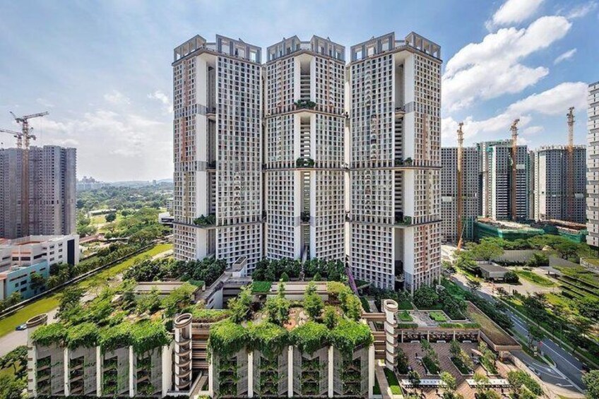 Un edificio residencial de varios pisos con un diseño arquitectónico único, rodeado de vegetación y otros edificios. 2