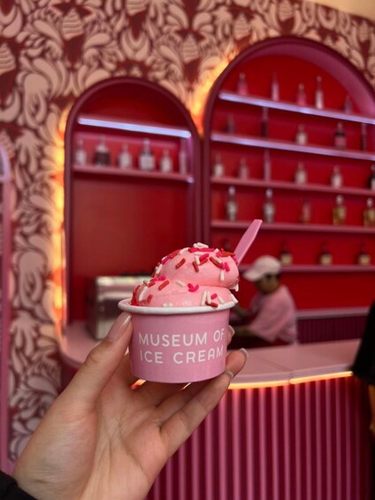A hand holding a pink ice cream cone with sprinkles, labeled 'Museum of Ice Cream'. 5