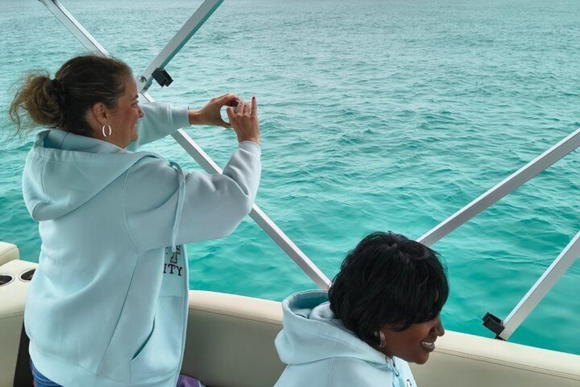 Eine Person in einer hellblauen Kapuzenjacke steuert ein Boot auf türkisfarbenem Wasser. 2