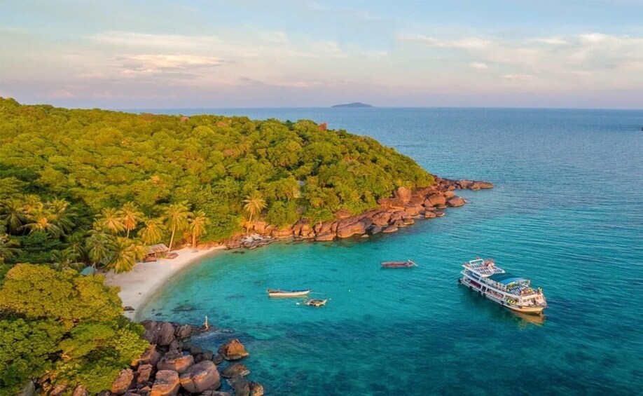A tropical beach with clear turquoise waters, a boat, and lush greenery. 4