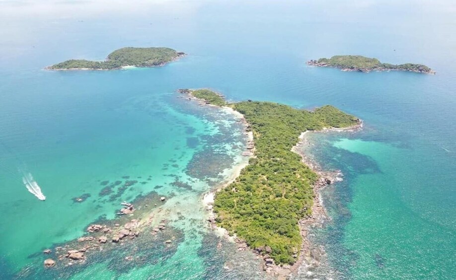 An aerial view of a coastal area with clear turquoise waters, a sandy beach, and lush green islands. 2