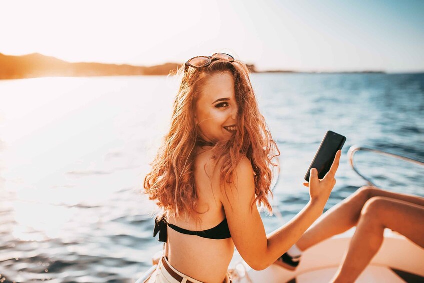 A person in a bikini on a boat, holding a smartphone. 5