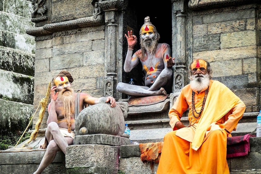 Three individuals sitting on stone steps in front of a temple. 2