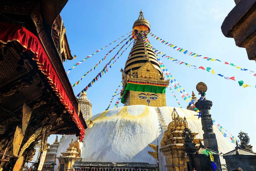 A large stupa with colorful prayer flags, surrounded by traditional architecture. 1