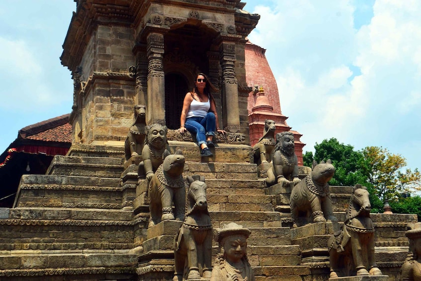 A person sitting on stone steps with intricate carvings of animals and figures. 3
