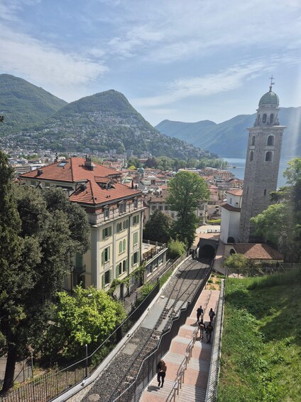 A town with a prominent tower, a bridge, and a mountainous backdrop. 1