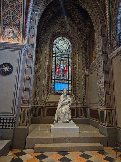 A statue in a church with a stained glass window behind it. 5