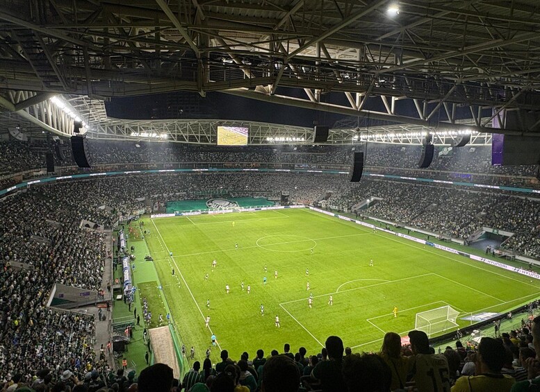 A large indoor stadium with a soccer field, surrounded by spectators. 4