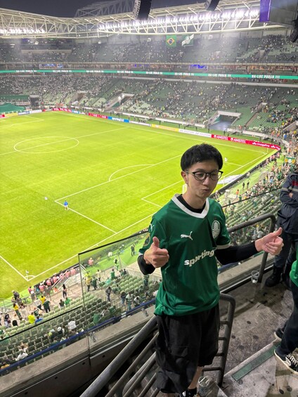 A stadium with a football field, spectators, and a person giving a thumbs-up. 2