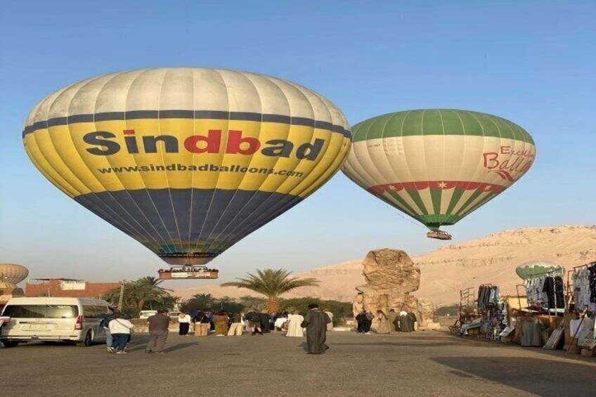 Dos globos aerostáticos, uno con la marca 'Sindbad', sobre un mercado con gente y puestos. 1