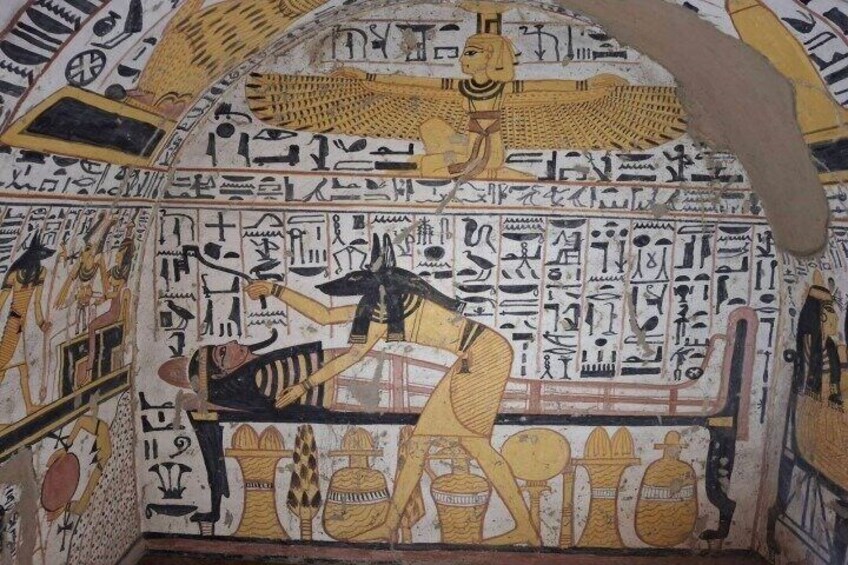 Interior de una tumba decorada con jeroglíficos, una figura sentada y un gran dios sol alado. 5