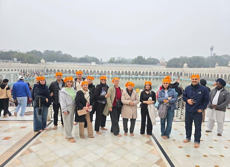 A group of people standing on a tiled platform with a historical building and arches in the background. 2